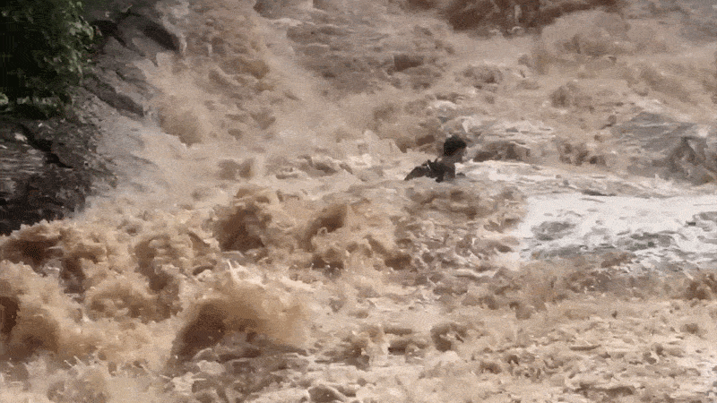 Tourists struggle in flood at waterfall